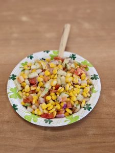 A close view of a colorful corn salad with fresh vegetables and spices on a paper plate at Kurla, Mumbai. The bright colors make it look tasty and inviting.
