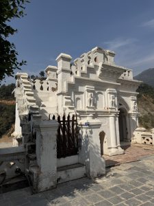 A partially weathered white structure with unique architectural features, including ornate walls and decorative elements. 
