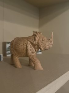 Small sculpture of a rhino on a wooden shelf