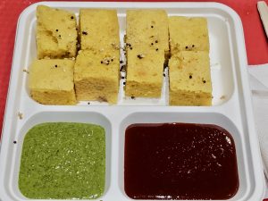 Soft yellow dhokla pieces served with green and red chutney in a tray. A light snack beautifully presented in Kurla, Mumbai. 
