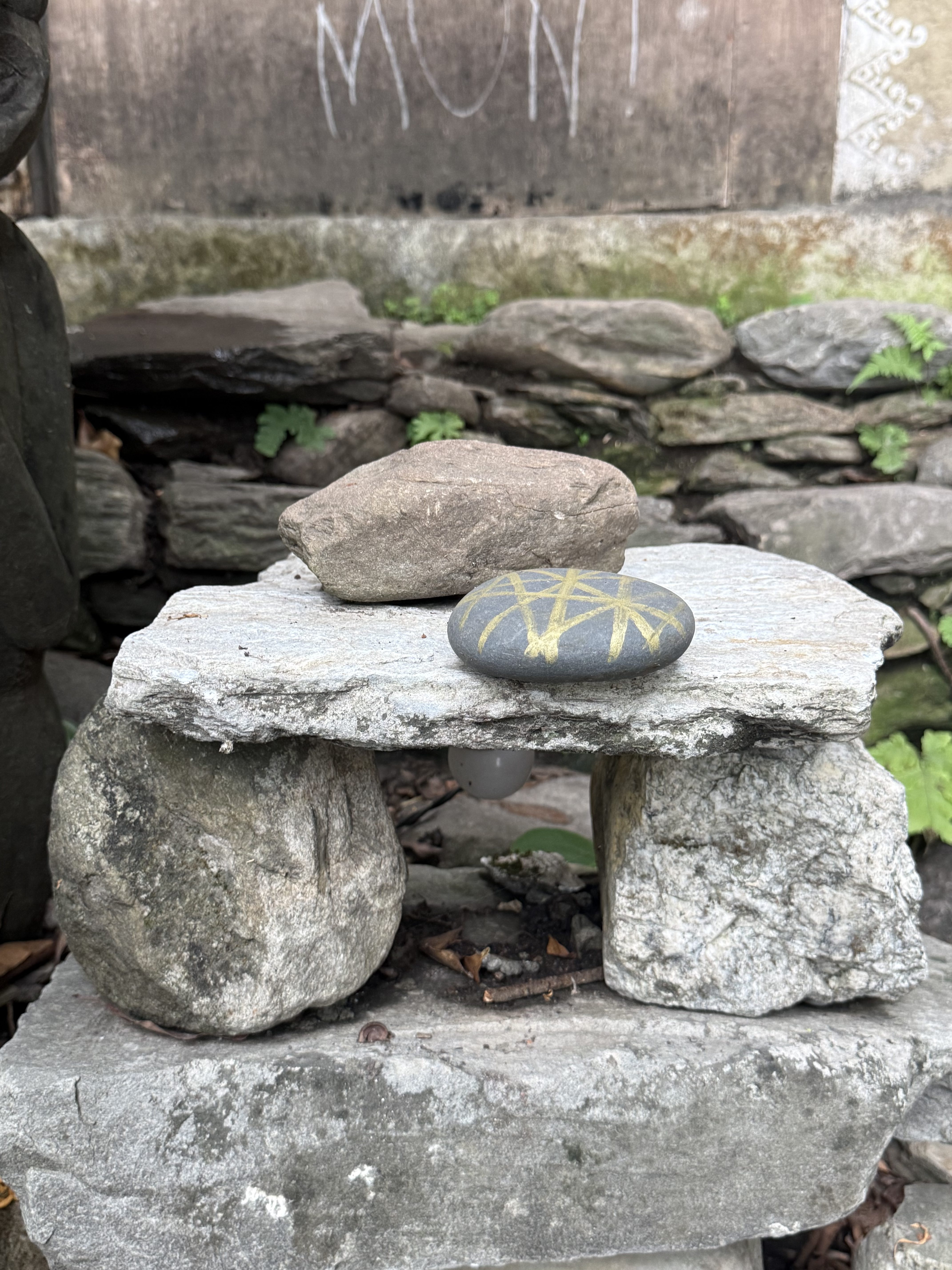 A small stone structure made of stacked stones, with two larger stones supporting a flat stone slab on top.
