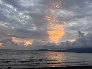 A calm beach at sunset with soft orange and pink colors in the sky.