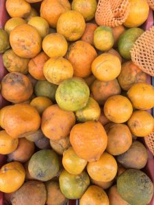 A basket filled with a vibrant pile of fresh oranges, showcasing their bright orange color and smooth texture