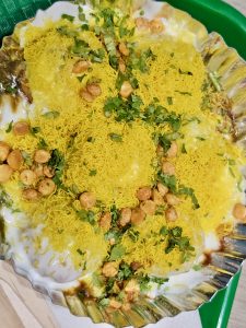 A tasty chaat topped with yellow sev, curd, chutney, and coriander leaves. A colorful street food dish from Kurla, Mumbai. 