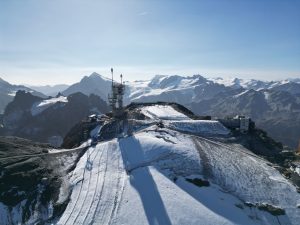 Snow-covered mountain peak in Switzerland with observation structures and surrounding alpine landscape.