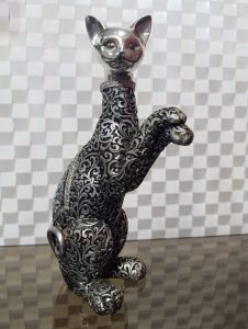 Cat sculpture with a silver head and a gray and black body decorated with plant patterns.