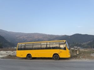 
A yellow bus parked beside a road with a mountainous background