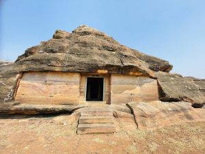 A rock-cut structure with a doorway built into natural stone. The earthy tones and rugged shape give a unique, ancient look. Captured at Aihole, Bagalkot, Karnataka.
