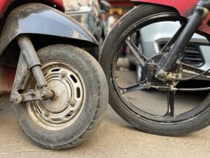 Close-up of scooty and bike wheels side by side on a pavement.