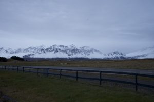 Road in Iceland with snow-covered mountains in the background.