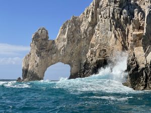 A coastal rock arch formation rising above turquoise waters in Mexico.