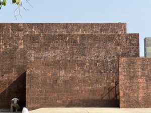 
A textured, rust-colored wall composed of stacked blocks, creating a geometric pattern. 
