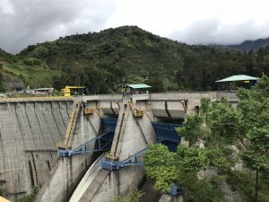 A large dam surrounded by green mountains, where engineering and nature come together in a striking landscape.