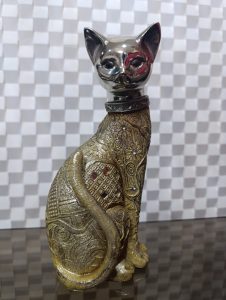 A cat sculpture with a silver head and a golden body, decorated with extravagant patterns and shiny stones.