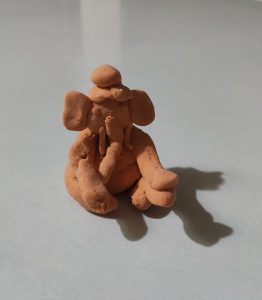 A simple clay idol of Lord Ganesha in a seated posture.
