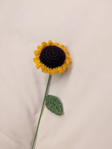 A crocheted sunflower sits against a light background
