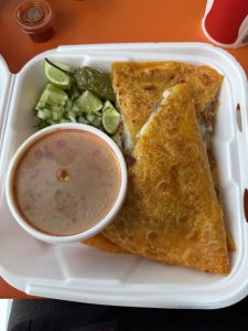 A plate of birria quesadillas accompanied by limes 