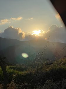 A glowing sunset over the mountains, with soft light breaking through the clouds and illuminating the natural scenery.
