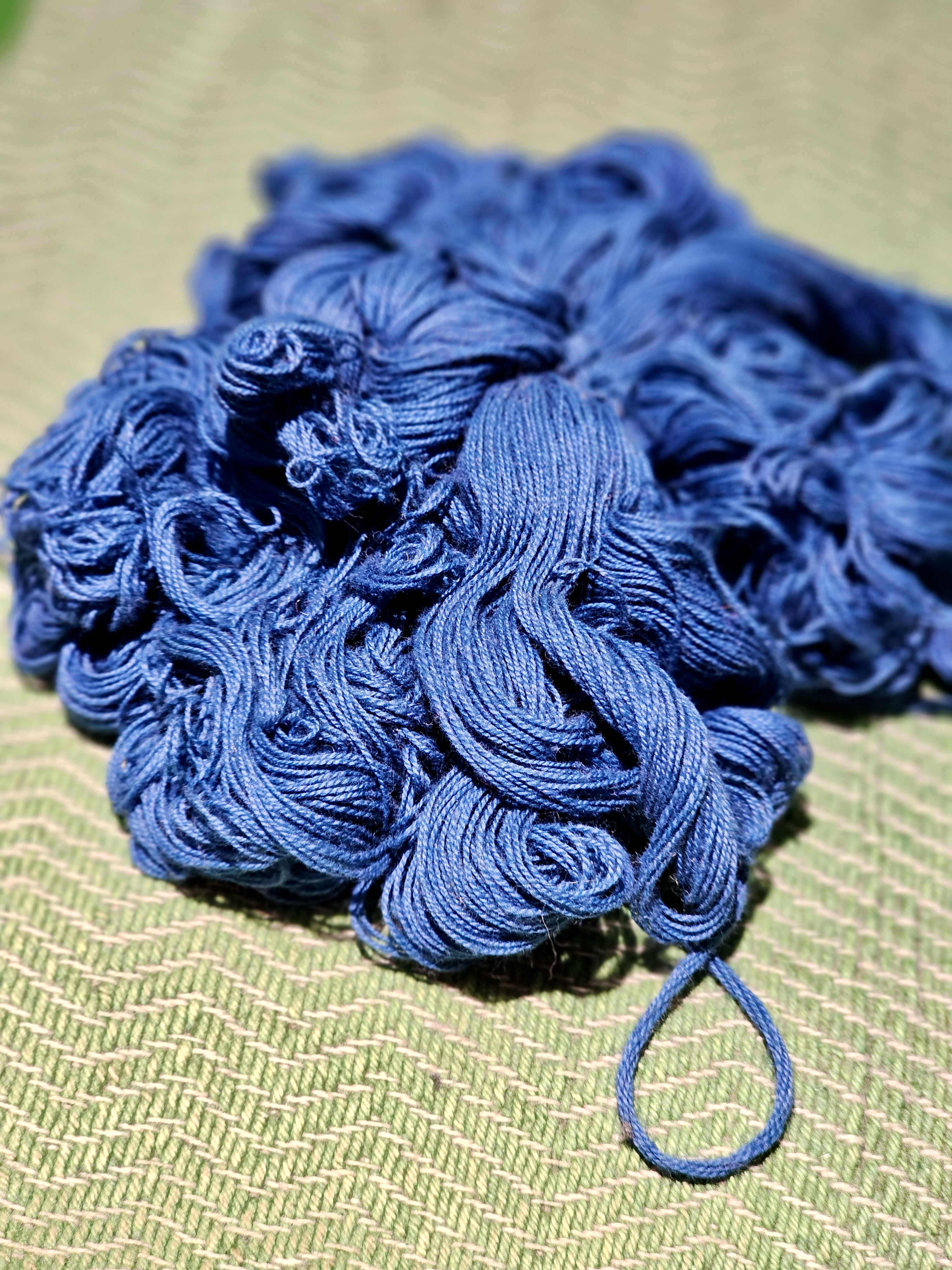 A bundle of deep blue threads placed on a textured surface, showing fine details and patterns at Chhatrapati Shivaji Maharaj Vastu Sangrahalaya, Mumbai.