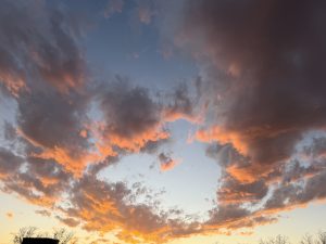 
A vibrant sunset sky filled with fluffy clouds in shades of orange, pink, and gray.
