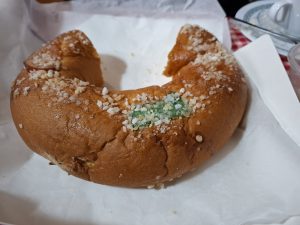 Round sweet bread with sugar on top. A slice of the round bread is missing.