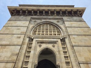 A close side view of the Gateway of India arch in Colaba, Mumbai, showing fine stone carvings and design. The low-angle shot adds depth and highlights the details.
