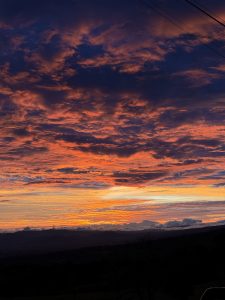 Dramatic sunset sky with vibrant orange and purple clouds over a distant landscape.