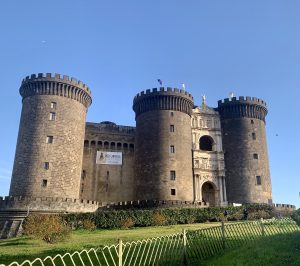 Castel Nuovo, Naples, Italy. Featuring an imposing medieval castle with three circular towers and different shades of brown bricks.