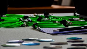 A horizontal close-up of several coiled bright green USB-C cables neatly arranged on a light gray surface.