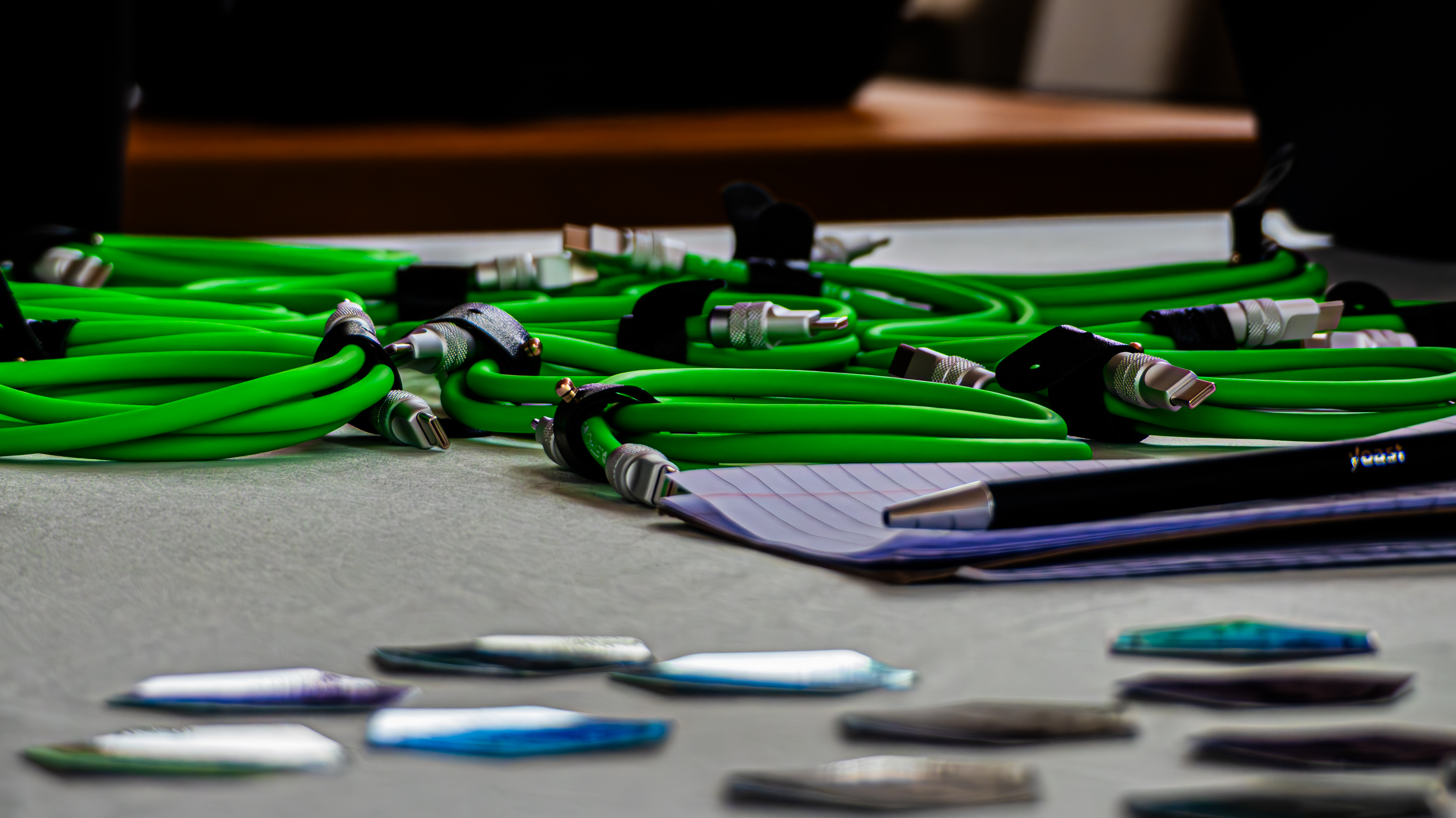 A horizontal close-up of several coiled bright green USB-C cables neatly arranged on a light gray surface.