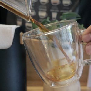 Pouring rich black coffee into a glass cup.