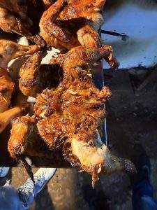 
A platter of grilled or roasted chicken, showcasing crispy, caramelized skin and char marks. 