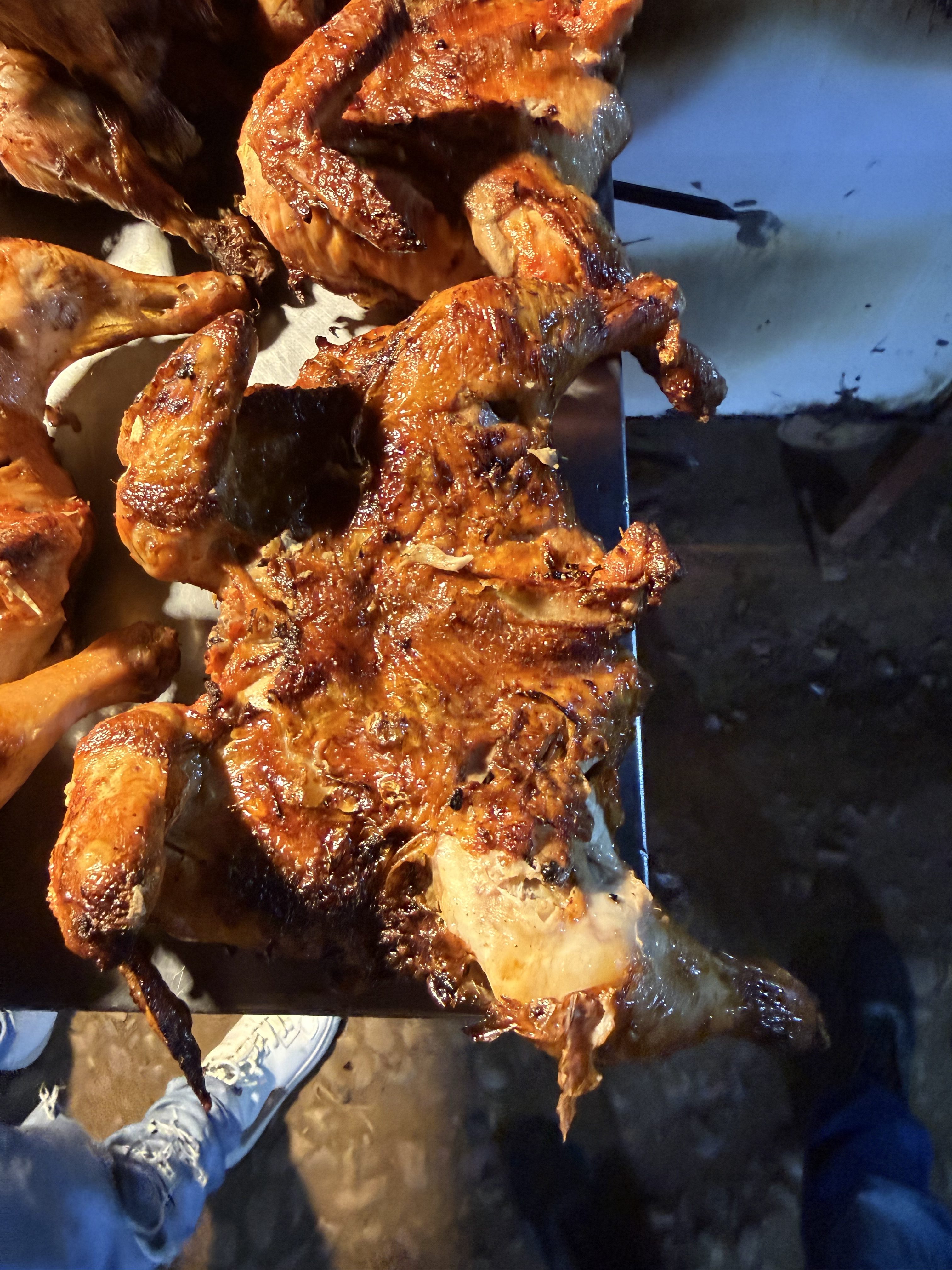 A platter of grilled or roasted chicken, showcasing crispy, caramelized skin and char marks.