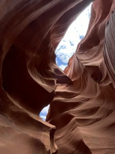 The sky is visible between red rock walls at Lower Antelope Canyon in Navajo territory.