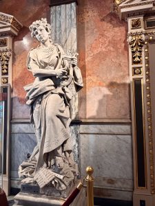 A sculpture of a woman playing a harp inside the National Theatre of Costa Rica, featuring detailed craftsmanship and a classic design.