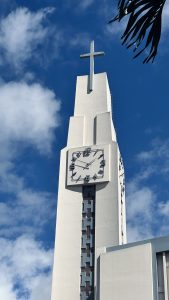Top part of a cathedral with a clear blue sky and scattered clouds in the background.