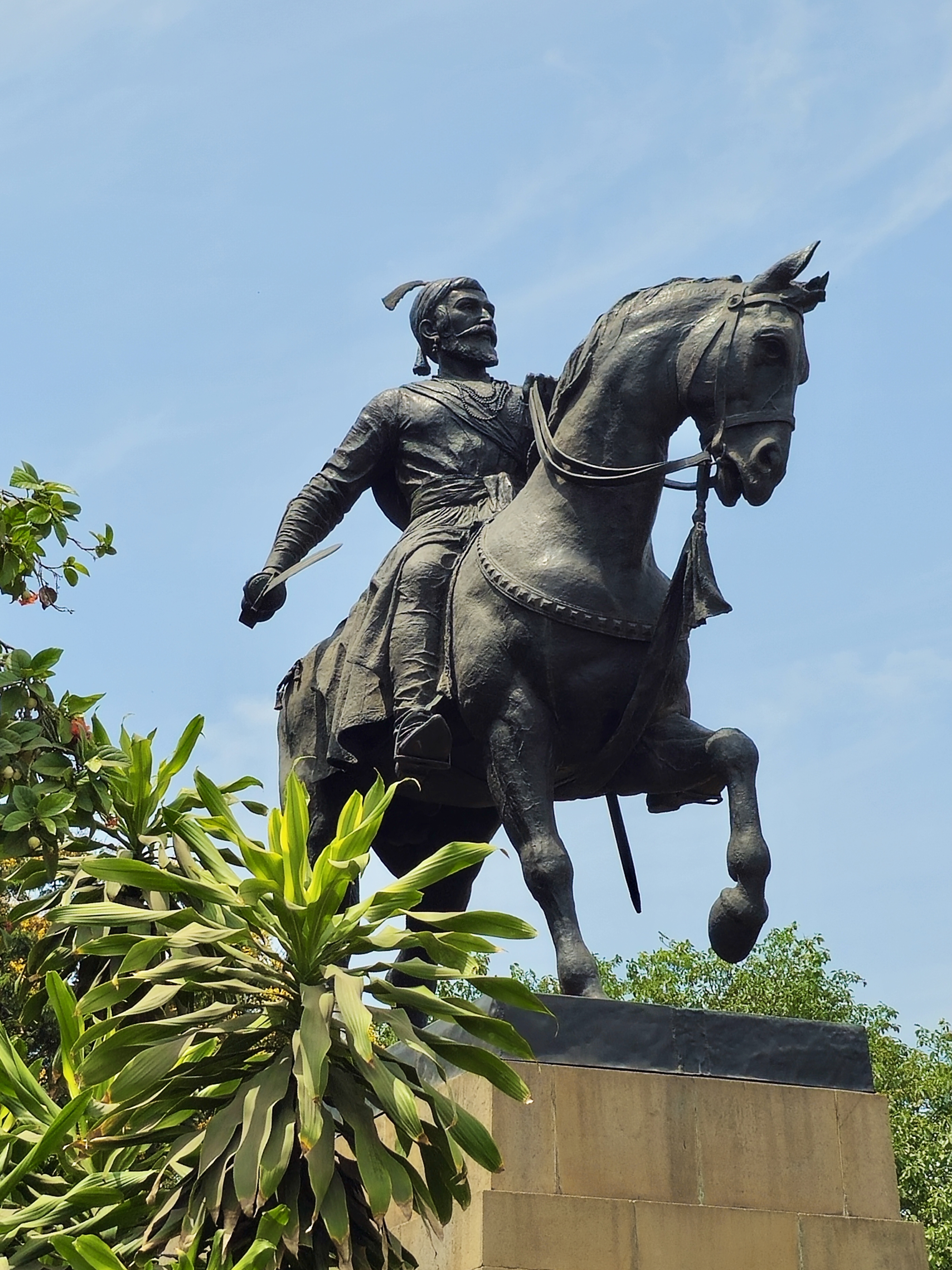A statue of Chhatrapati Shivaji Maharaj on a horse in Colaba, Mumbai (near Gateway of India). The strong pose and upward angle give the scene a powerful, heroic feeling.