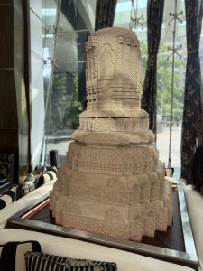 A detailed stone sculpture with intricate carvings sits on a sleek rectangular table in Mumbai.