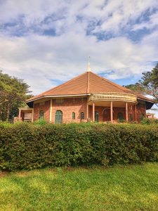 A brick church with a brown tiled roof, arched windows, and a hedge in front. #JinjaPhotoWalk