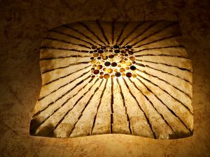 A warm, glowing ceiling light with artistic patterns spreading from the center. The soft golden light creates a cozy and elegant look in Worli, Mumbai.