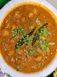 Rich and spicy chole curry garnished with coriander and green chilies. A flavourful dish served hot in Kurla, Mumbai. 