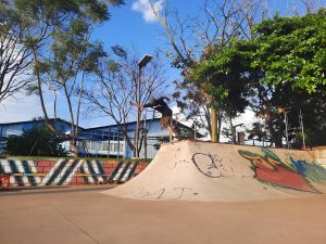 Skateboarder at the Belen de Hereida skate park in full motion, captured just as he reaches the top of a ramp in an urban park. Under a clear, deep blue sky.