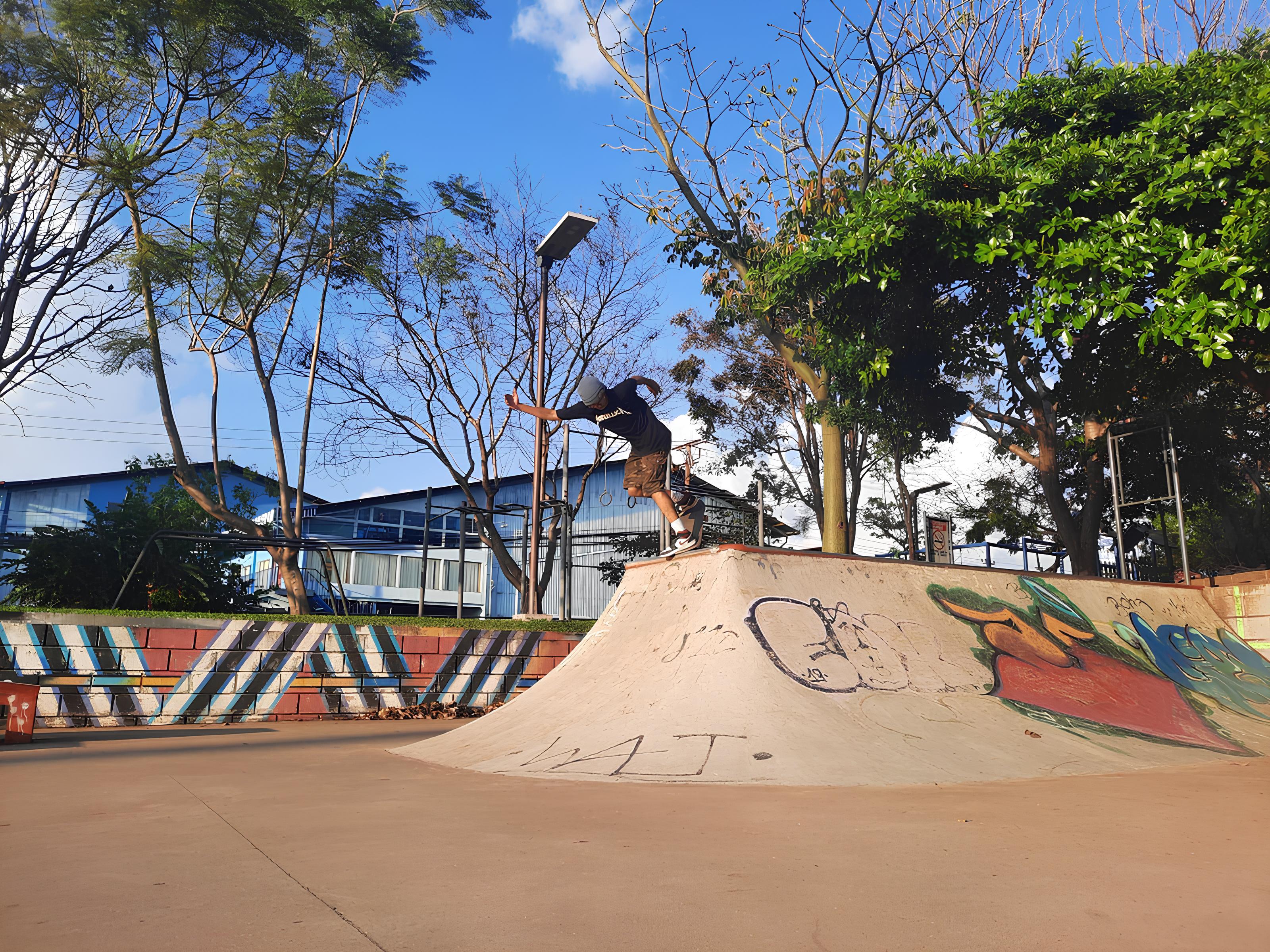 Skateboarder at the Belen de Hereida skate park in full motion, captured just as he reaches the top of a ramp in an urban park. Under a clear, deep blue sky.