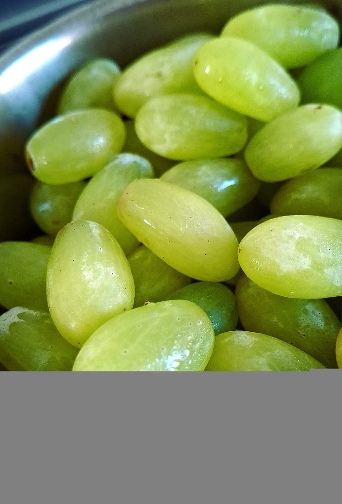 Fresh green grapes in a stainless steel bowl, close-up