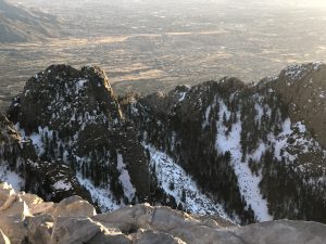 Snowy cliffs overlook a vast landscape in soft golden sunlight, calm and beautiful.