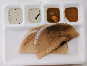 
A plate with three golden-brown dosa, a type of thin South Indian crepe, arranged in a semi-circle.