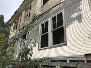 An old wooden house with weathered walls and broken windows, showing the passage of time in a quiet and rustic setting.