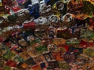A close-up view of a collection of crushed beverage cans in various colors and designs, showcasing a mixture of shiny metallic surfaces and colorful labels.