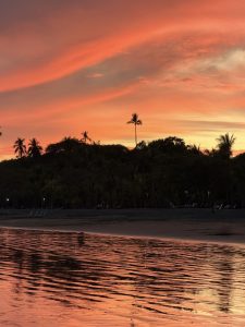 Sunset at Playa Mal País, Costa Rica, with deep orange sky over the forest.