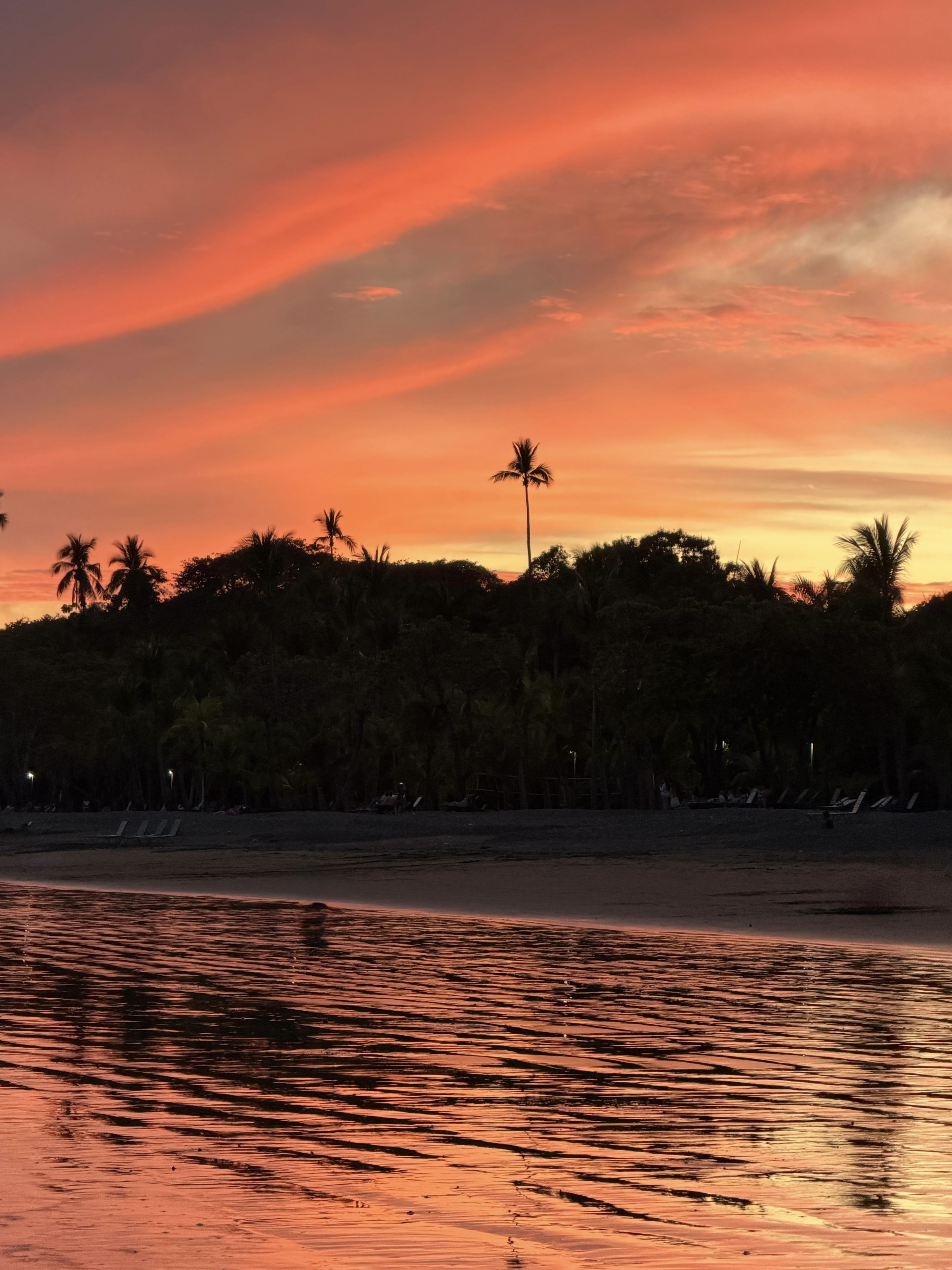 Sunset at Playa Mal País, Costa Rica, with deep orange sky over the forest.